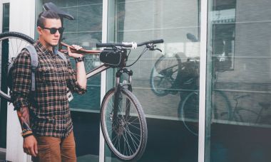 Gözlüklü yakışıklı genç bisikletçi bisiklet onun omuz Street günlük rutin yaşam tarzı üzerinde taşır.