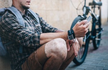 Genç bisikletçi bisiklet ve onun Smartphone vasıl arıyorum yanında oturan adam. Sokak yaşam tarzı kentsel günlük kavramı