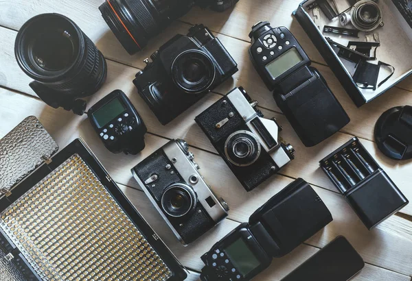 Vintage filmkamera, Dslr digitalkameror och tillbehör på vit trä bakgrund teknik utvecklingskoncept. Ovanifrån — Stockfoto