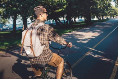Genç adam sürme On bisiklet içinde yaz Park, bisikletçi ın motion, arkadan görünüş. Dinlenme kavramı kentsel yaşam tarzı