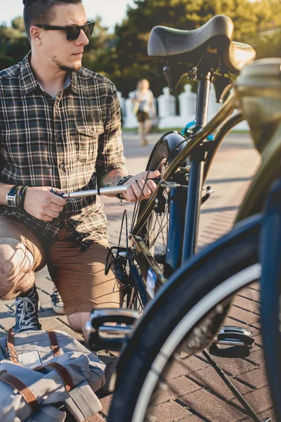 Guapo joven ciclista bombas bicicleta rueda mantenimiento transporte concepto — Foto de Stock