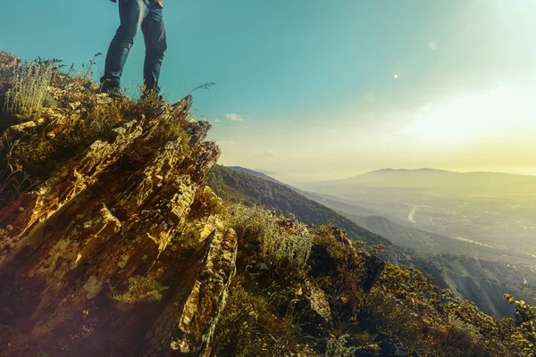 Par de pés humanos fica no topo da montanha contra o fundo do vale ensolarado. Conceito de viagem, aventura e descoberta — Fotografia de Stock