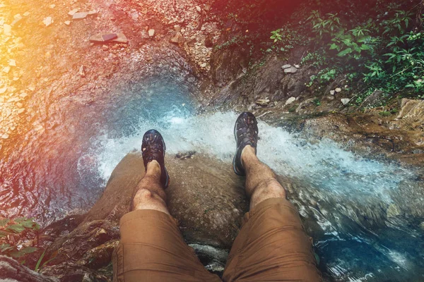 Viajante Masculino sentado no penhasco com vista para a cachoeira. Viagem Estilo de vida conceito de férias de aventura — Fotografia de Stock