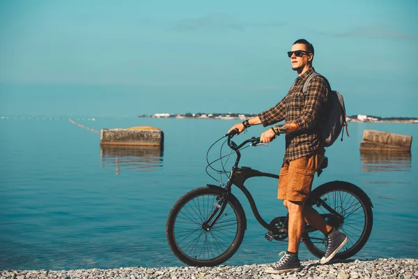 Jonge mannelijke fietser met de fiets lopen op de kust en genieten van uitzicht op zee. Concept van de activiteit van vakantie reizen — Stockfoto