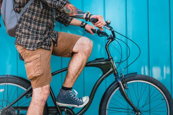 Ung Man cyklist med tatuering sitter på cykel nära blå vägg dagliga livsstil vilar storstadskoncept — Stockfoto