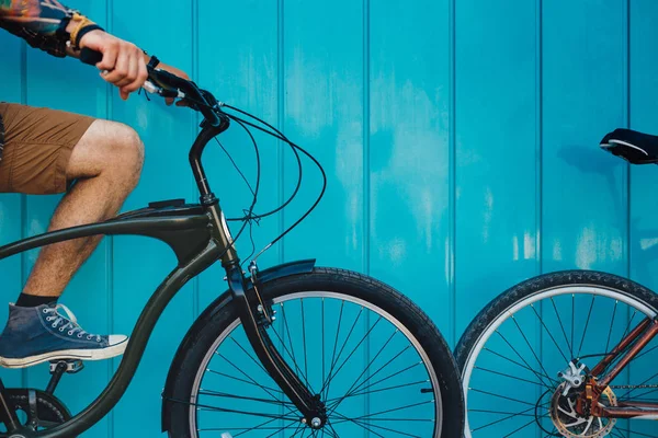 Joven irreconocible sentado con una bicicleta a lo largo de una pared azul Antecedentes Estilo de vida diario Urban Resting Concept — Foto de Stock