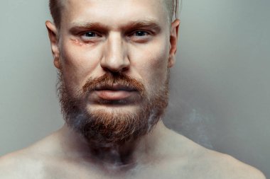 Sigara dumanı içinde onun yüzünde bir yara izi ile gergin, odaklanmış genç adam portresi. Kötü alışkanlık kavramı