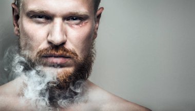 Sigara dumanı içinde onun yüzünde bir yara izi olan gergin, odaklanmış adam portresi