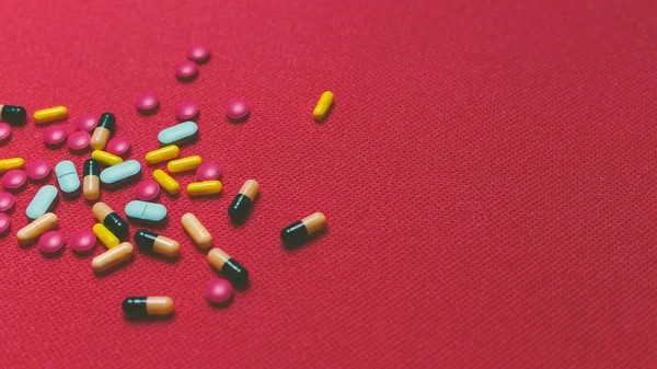 Verschillende kleurrijke pillen, tabletten en Capsules op rode achtergrond — Stockfoto