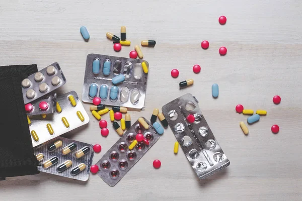 Kapható, sztetoszkóp, és különböző színes tabletták, tabletta, kapszula, fehér fa háttér, felülnézet — Stock Fotó