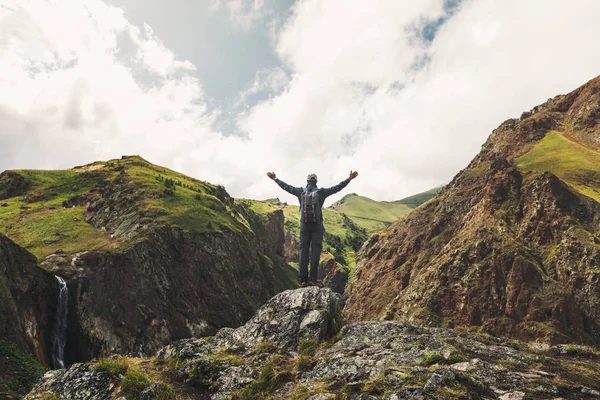 Hombre joven explorador feliz de pie con los brazos levantados en las montañas de verano, Vista trasera — Foto de Stock