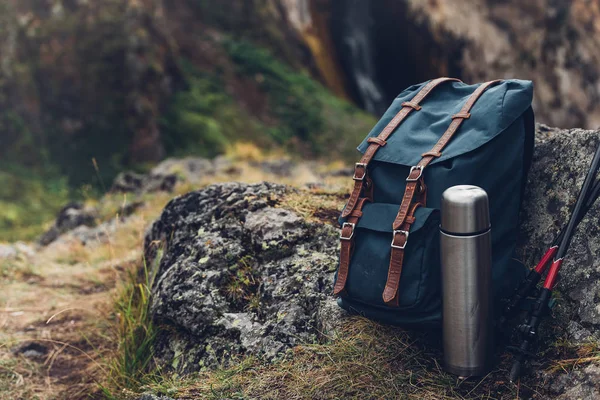 Mochila Hipster Azul, Termos y Trekking Polos Primer plano, Vista frontal. Bolsa de viajero turístico en el fondo de rocas. Aventura Senderismo Concepto al aire libre — Foto de Stock