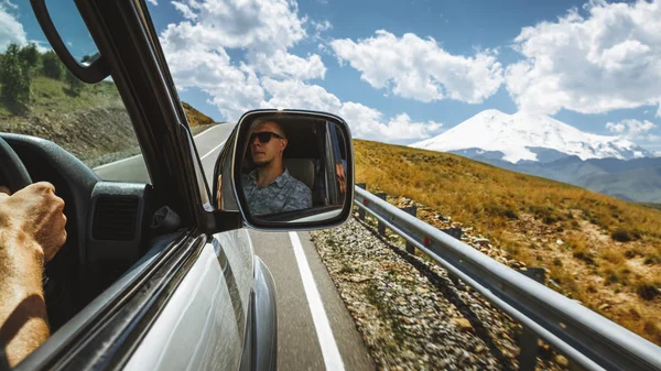 Fahren auf der Bergstraße. Fahrer in den Seitenspiegel eines Autos. Roadtrip-Lifestyle-Konzept — Stockfoto