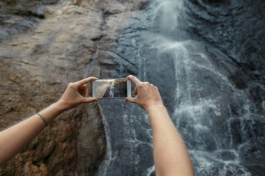 Turizm şelale cep telefonu ile fotoğraf çekmek. Seyahat macera hedef açık kavramı