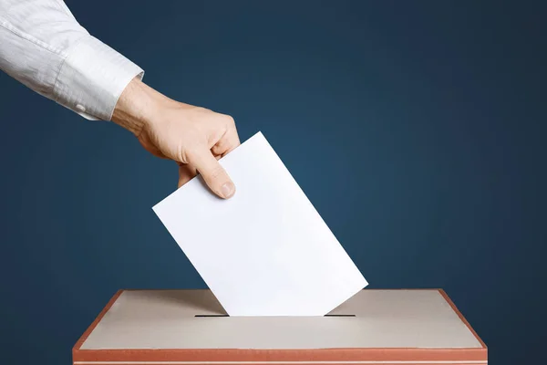 Seçmen oy oy yukarıda elinde tutar zarf. Mavi arka plan. Demokrasi kavramı
