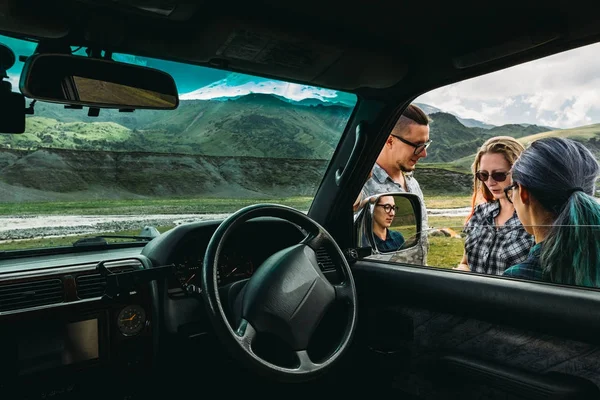 Drei Freunde in der Nähe des Autos besprechen die Route während der Fahrt — Stockfoto