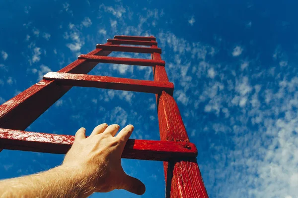 男人的手，伸手去拿红色梯子通向一片蓝天。发展动机职业增长概念 — 图库照片