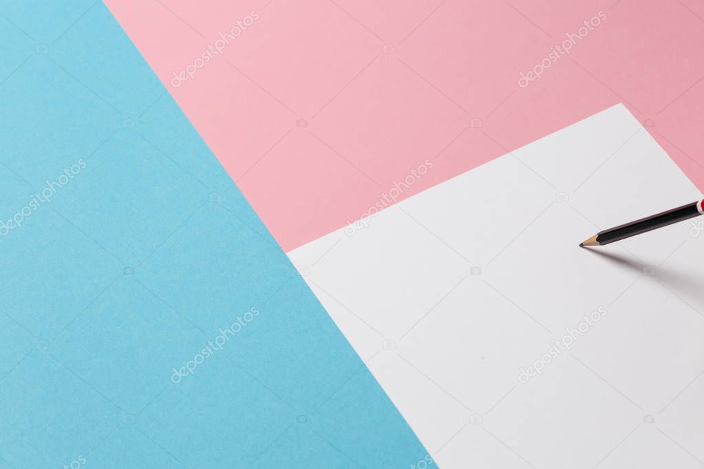 White Sheet Of Paper, Black Pencil On A Blue And Pink Surface. Creative Concept