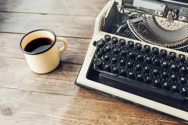 Máquina de escribir y una taza de café caliente en una mesa de madera — Foto de Stock