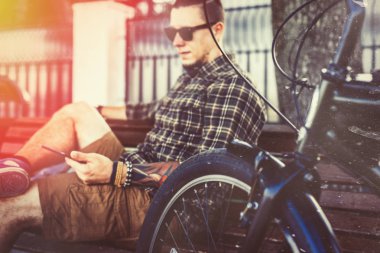 Bankta oturan ve Tablet, tonda ve çizikler kullanan genç adam