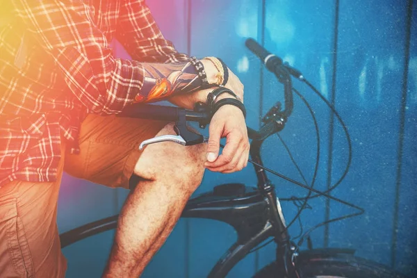 Hombre irreconocible sentado en una bicicleta cerca de la pared azul y Ligth Antecedentes Estilo de vida diario Urban Resting Concept Toned And Scratches — Foto de Stock