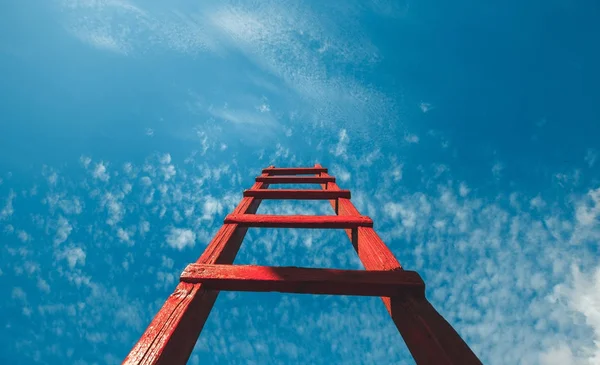 Kırmızı merdiven aittir mavi gökyüzü karşı ön görünümü. Geliştirme motivasyon kariyer büyüme kavramı