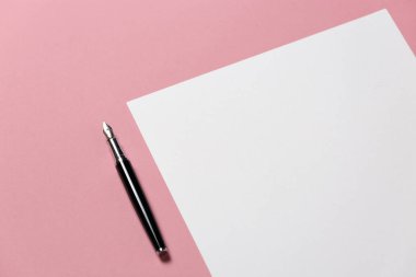 Pembe arka plan, üstten görünüm üzerinde boş bir sayfa üzerinde kalem yatıyor. Ofis alanı yaratıcılık minimalizm kavramı