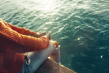 Genç kız elinde dürbün ile bir Pier üzerine oturur ve doğa, arkadan görünüş görünümünü sahiptir. İzci Yolculuk tutkusu kavramı