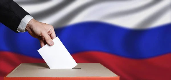 Voter Holds Envelope In Hand Above Vote Ballot On Russia Flag Background. Freedom Democracy Concept