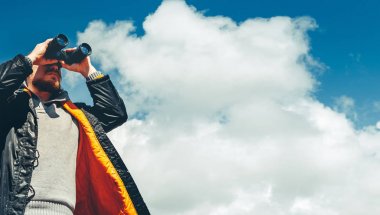 Seyahat arama kavramı. Dürbün gökyüzüne karşı mesafe bakarak adam hiking. Düşük açılı noktası ateş