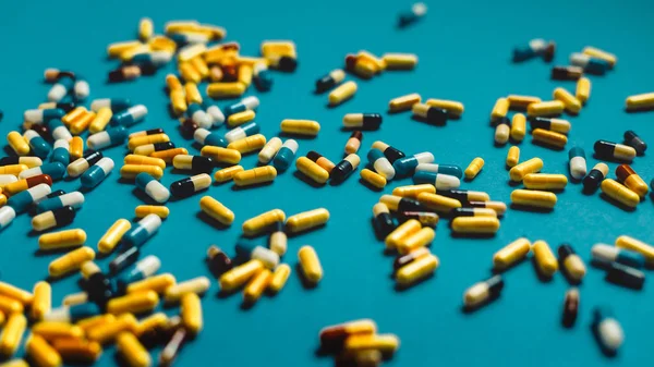 Különböző színes tabletták, kék alapon, a szelektív összpontosít. M — Stock Fotó