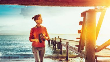 Kız Gezgin deniz kıyısında elinde dürbün ile Pier yakınındaki ve doğa, manzarayı ön görünüm