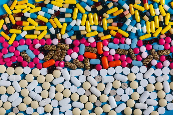 Sor fehér és színes tabletták a kék háttér, felülnézet. Kreativitás-gyógyszer fogalma — Stock Fotó