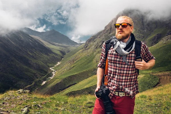 Pěší turistika dobrodružství cestování Blogger koncept. Hezký mužský cestovatel s vousy a digitální fotoaparát těší letní Mountain View — Stock fotografie