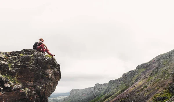 Jovem homem bonito caminhante sentado no topo e desfrutar de vista do vale da montanha — Fotografia de Stock