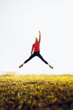 Elleri havada atlayan genç atletik bir kız. Spor, sağlıklı yaşam tarzı ve başarılı olma kavramı.