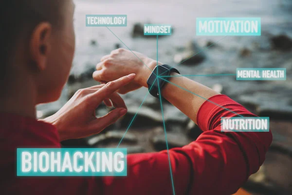 Concepto de Biohacking, Tecnología Moderna en Salud y Deportes. La mujer usa un reloj inteligente en su mano para entrenar un estilo de vida saludable, Vista desde atrás — Foto de Stock