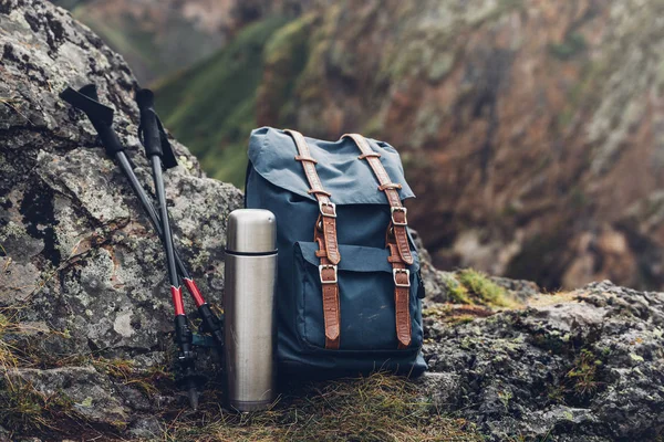 Mochila Hipster Azul, Termos y Trekking Polos Primer plano, Vista frontal. Bolsa de viajero turístico en el fondo de rocas. Aventura Senderismo Turismo Concepto Exterior —  Fotos de Stock