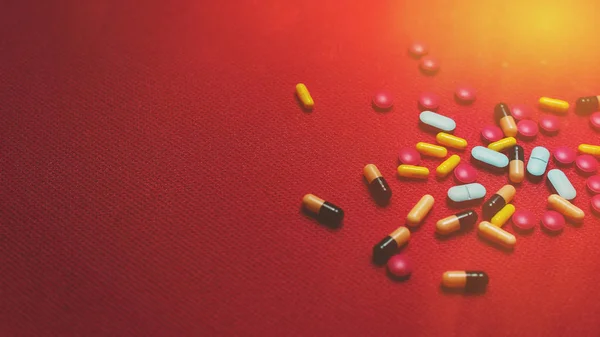 Sortiment farmaceutické medicíny pilulky, tablety a kapsle na červeném pozadí s kopírovacím prostorem — Stock fotografie