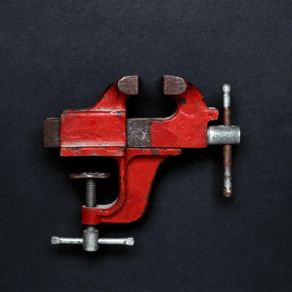 Ferramenta de trabalho em metal - braçadeira de mão mecânica vintage vermelha no fundo cinza com espaço de cópia — Fotografia de Stock