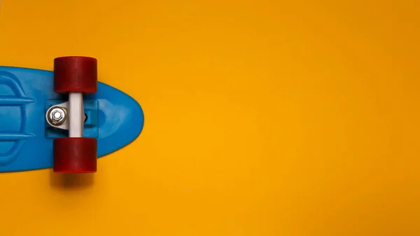 Skateboardkreuzer Mit Blauem Deck Und Roten Rädern Auf Gelbem Hintergrund — Stockfoto