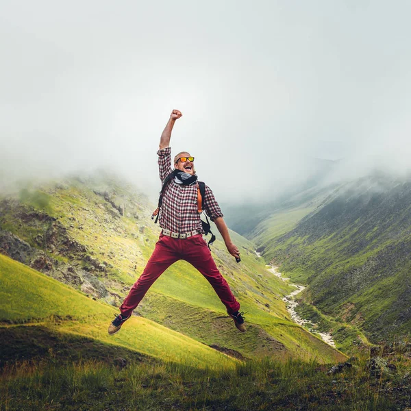 Man traveler jumps on background of mountain. Concept of outdoor adventure  motivation wanderlust — Stock Photo, Image