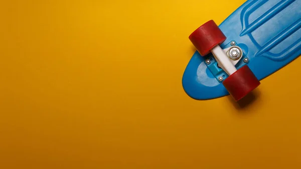 Skateboard Křižník Modrou Palubou Červenými Koly Žlutém Pozadí Horní Pohled — Stock fotografie