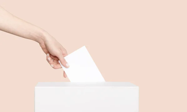 Civilized Equal Rights Concept. Female Hand Lowers Ballot In Ballot Box On Light Suntan Peach Background