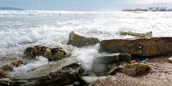 Foamy waves roll on rocky beach