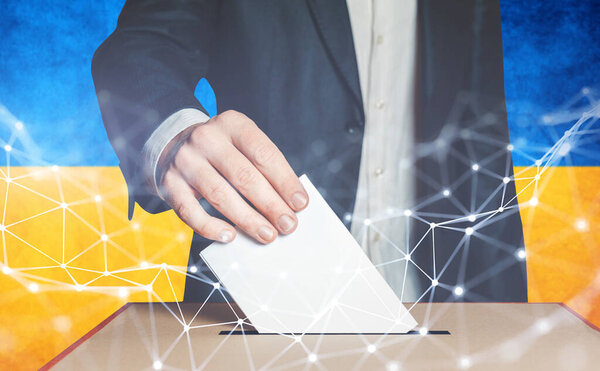 Человек-избиратель кладет бюллетень в урну для голосования на фоне украинского флага
