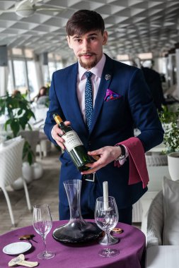 Genç şarap garsonu kırmızı şarap ikram ediyor.
