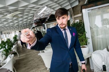 Genç şarap garsonu kırmızı şarap ikram ediyor.