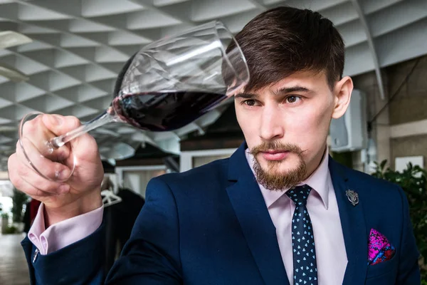 Genç şarap garsonu kırmızı şarap ikram ediyor.
