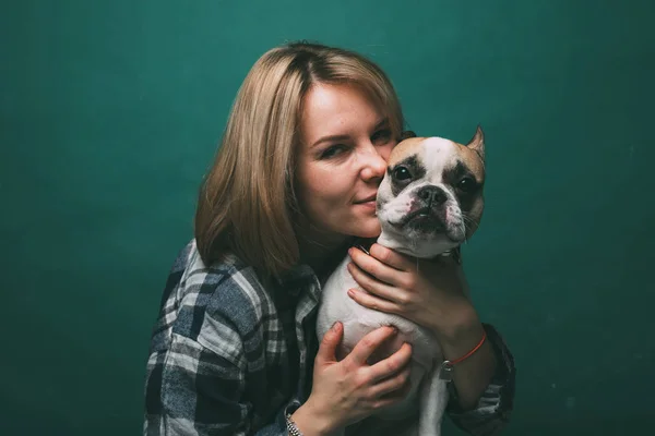 young girl and hugs a french bulldog on a green background